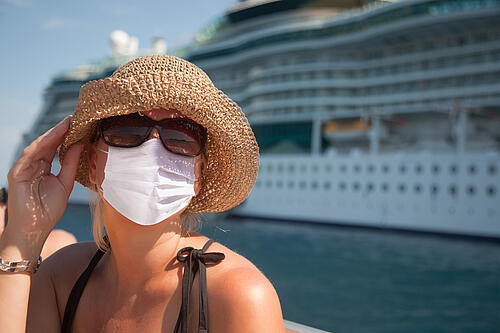 Woman wearing a mask in front of cruise ship