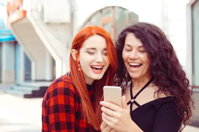two surprised girls looking at phone
