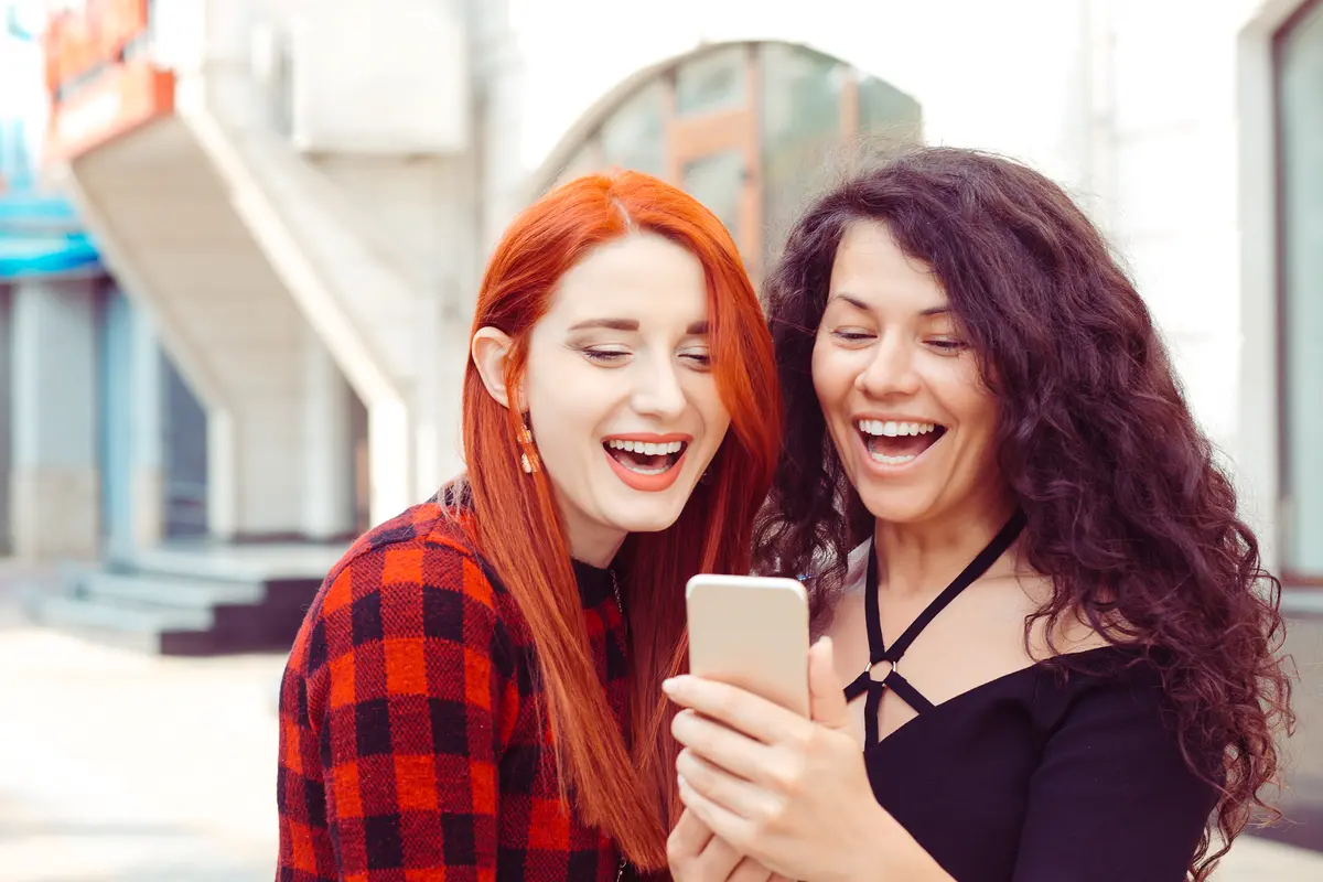 two surprised girls looking at phone