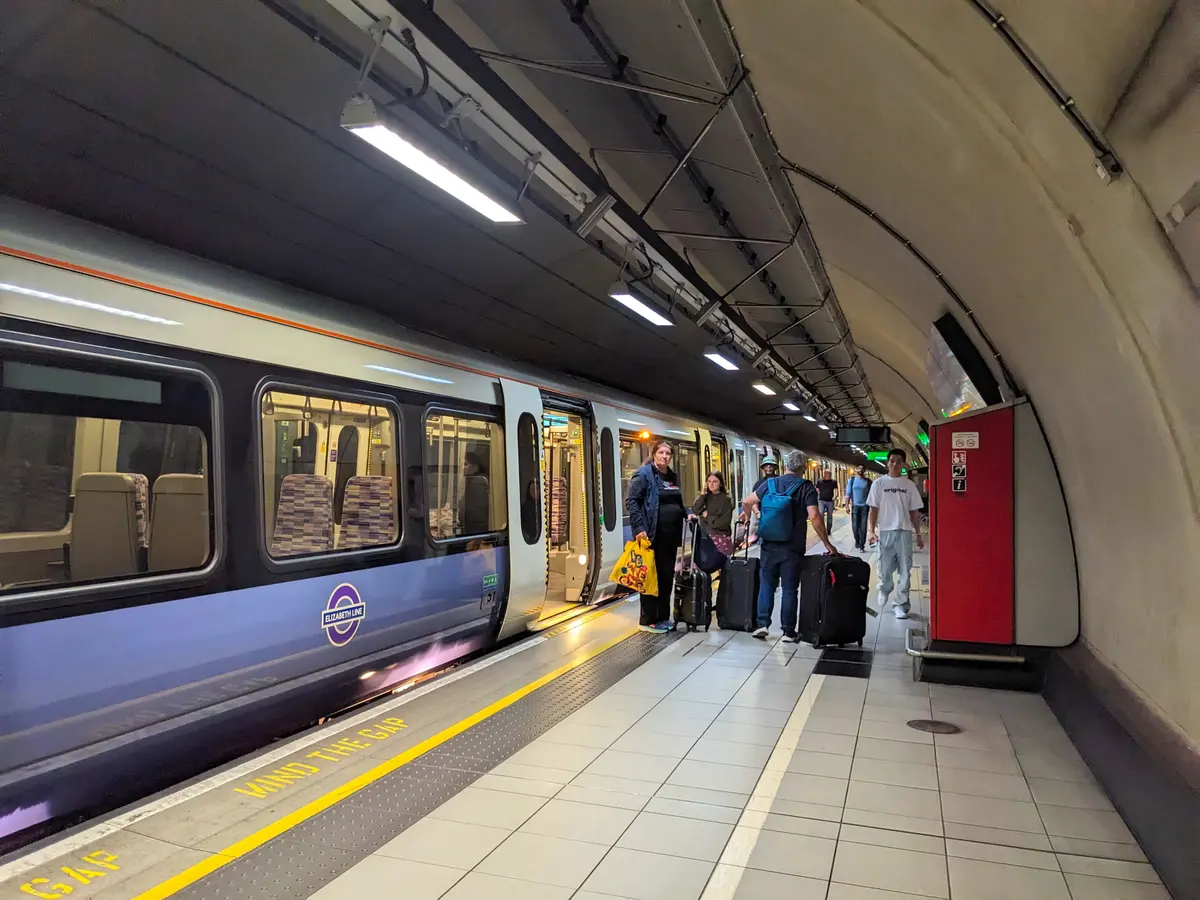 Passengers and Elizabeth Line train at busy Heathrow Airport station platform