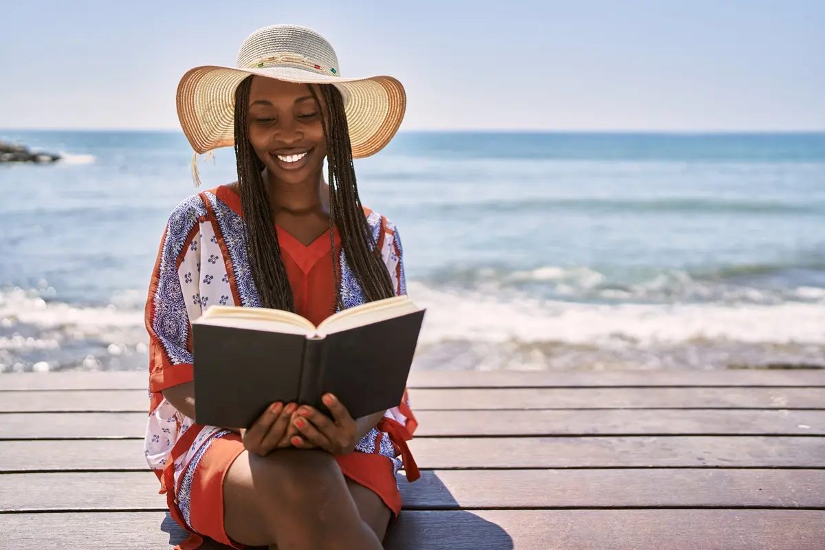 Woman reading a book by the beach